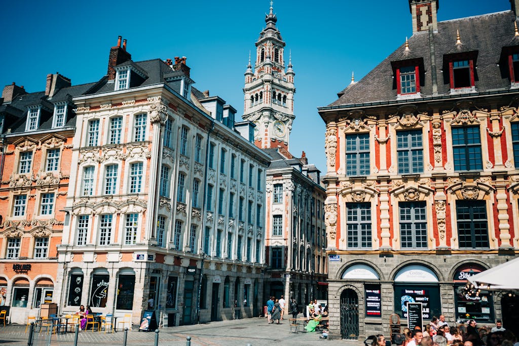 Ornate townhouses and belfry in Lille's Grand Place on a sunny day, showcasing local landmarks.