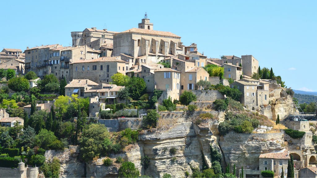 Scenic view of a historic hilltop village in Provence, France, under a clear blue sky.