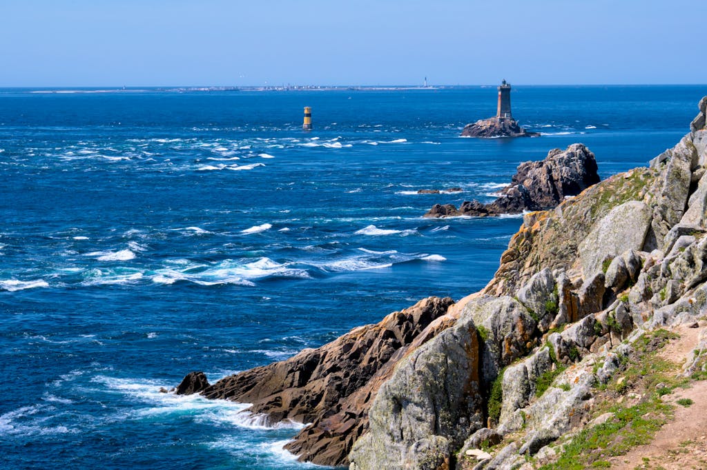 Stunning view of Plogoff coastline, featuring rocky cliffs and lighthouses in Brittany, France.