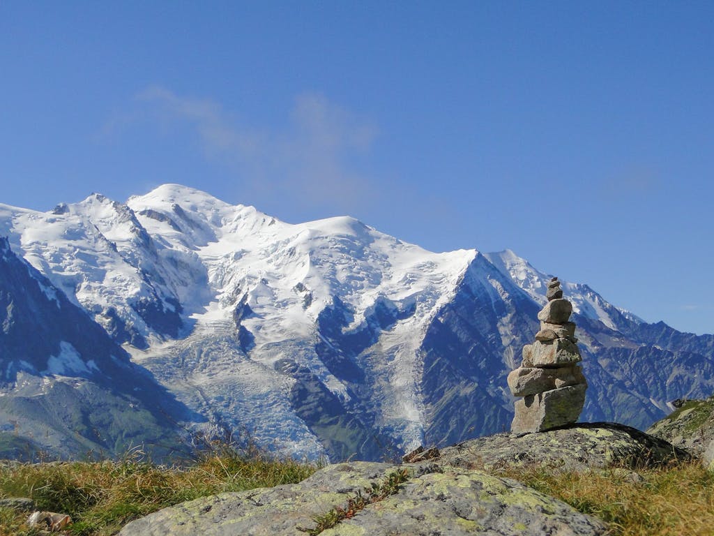 Tranquil view of Mont Blanc with rock balancing art in the foreground, depicting serene alpine nature.